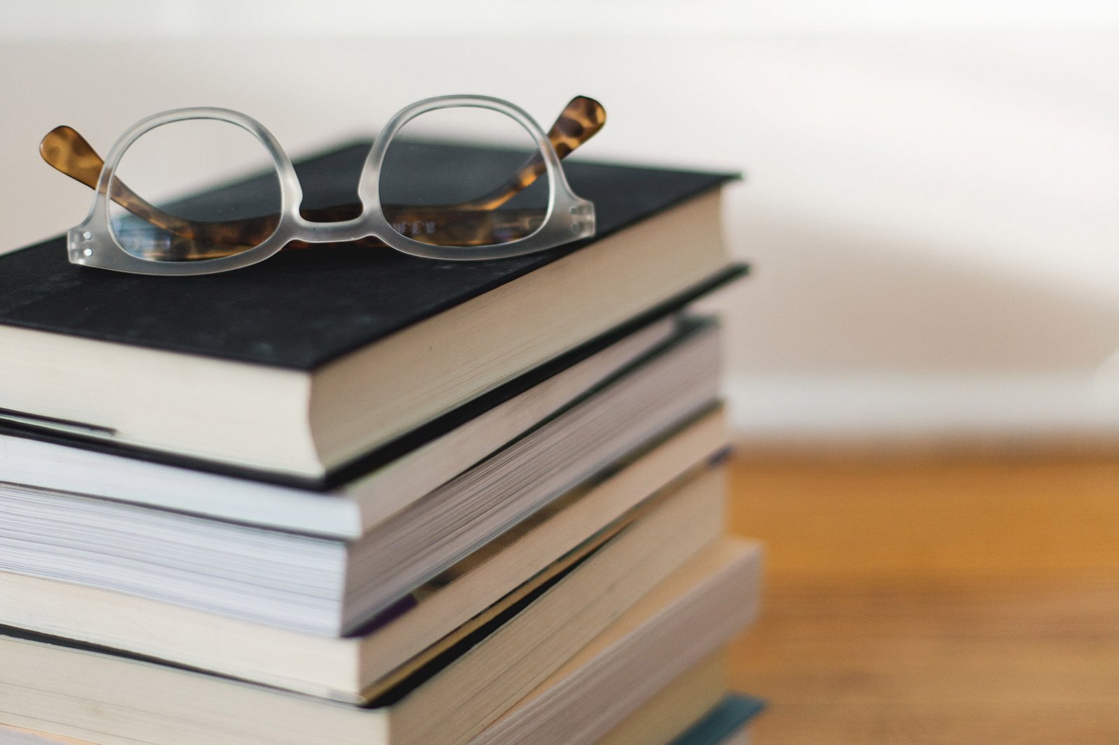 Un paio di occhiali posato su una pila di libri.